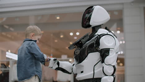 the-boy-stretches-out-his-hand-to-the-robot-for-a-handshake